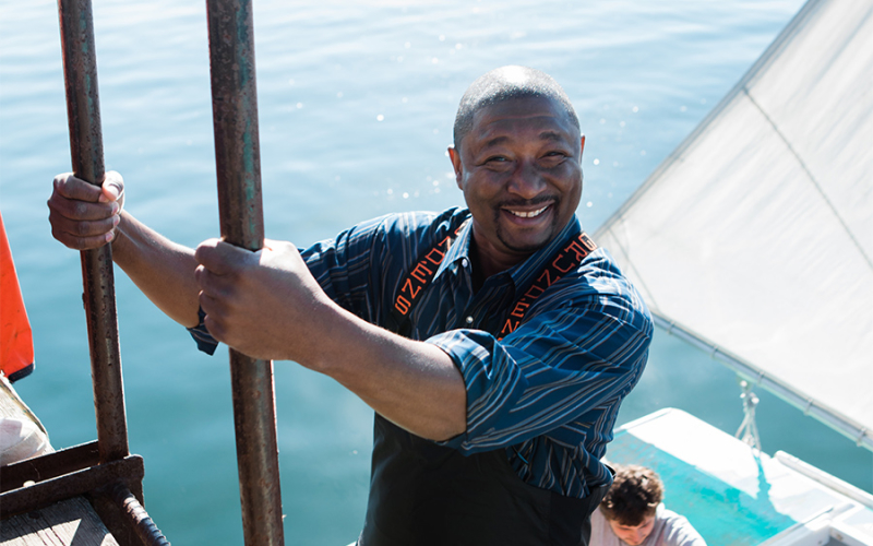 A photo of one of our Cousins Maine Lobster Memphis and Oklahoma City franchise owners smiling as he climbs down a ladder onto a fishing boat in Maine.