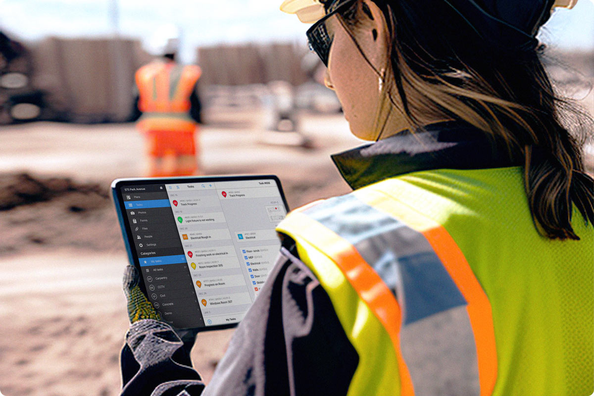 A female construction worker using Fieldwire on her iPad in the field. She is looking at the scheduling functionality of Fieldwire to plan the work ahead. 