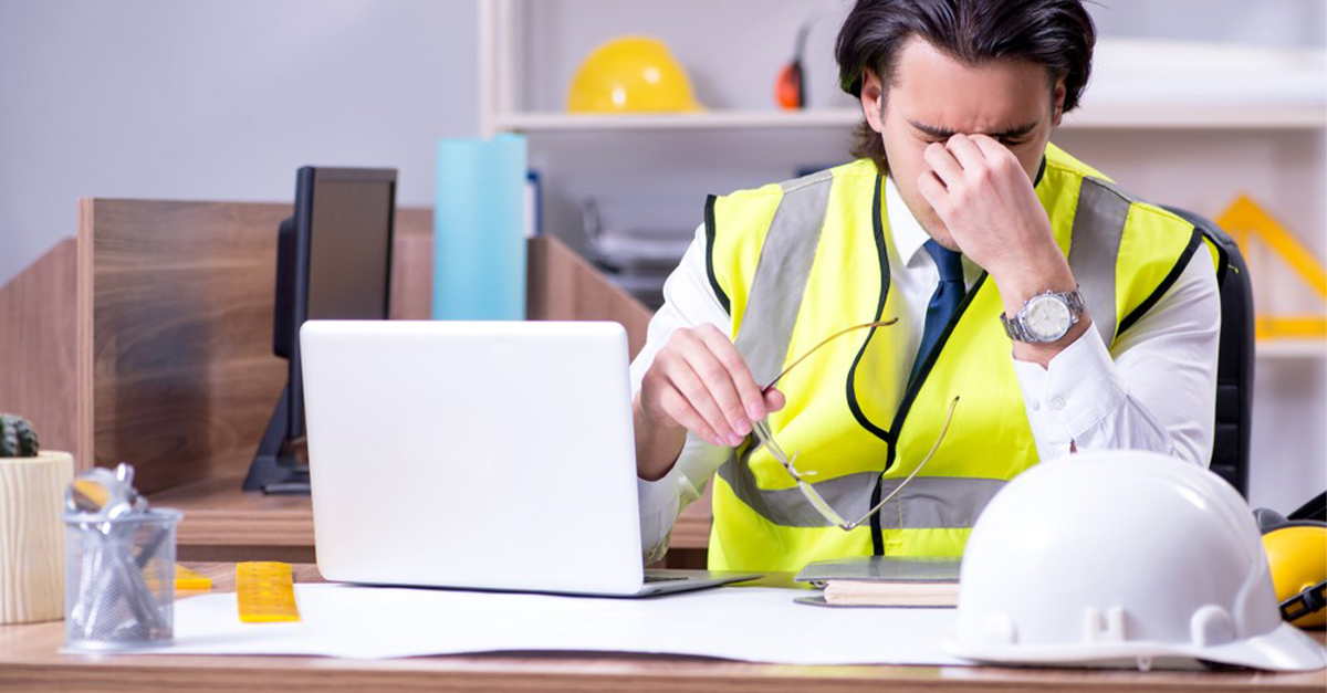 A project manager in the office stressed out about changes requested to a project and managing requests on paper plans, email and phone calls.