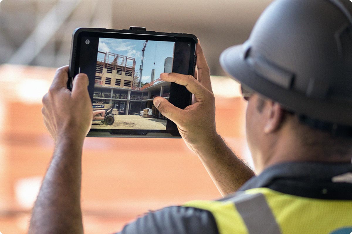 An inspector is using their iPad to take a picture of the construction site. Logging the picture for documentation purposes on the Fieldwire application.
