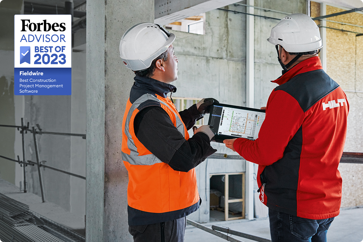 Un employé de Hilti sur un chantier avec un ouvrier du bâtiment examinant des plans dans Fieldwire sur une tablette.