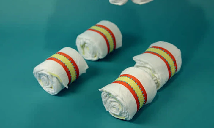 おむつを5枚重ねてベビーカーの車輪部分を作ります。輪ゴム部分が見えないように最後にリボンで飾りましょう。グルーガンを使ってベビーカーの箱の底に取り付けます。