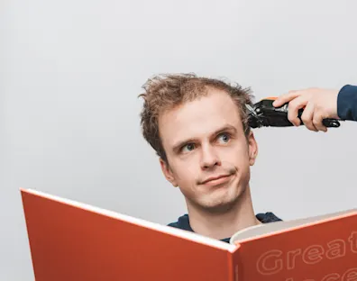 chico leyendo un libro mientras le cortan el pelo