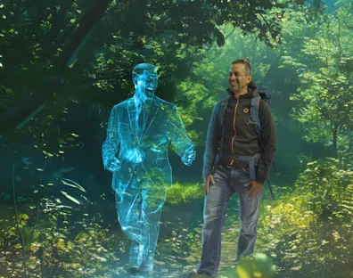 Image of a guy walking in the forest with an hologram walking together and laughing