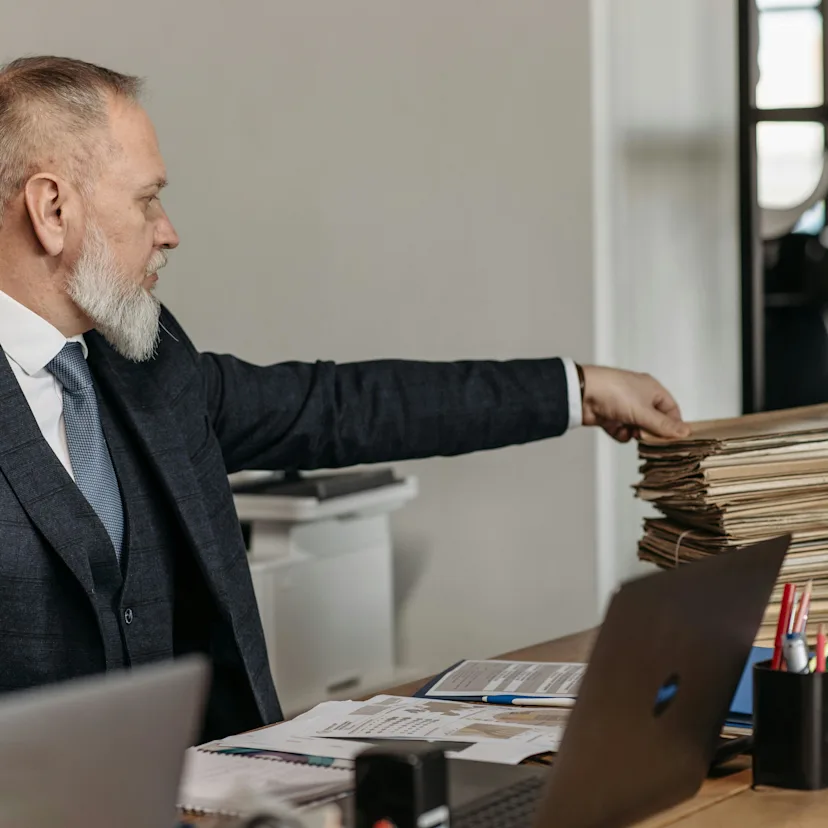 Imagen de un hombre de barba serio, con un cúmulo de papeles Imagen de un hombre de barba serio, con un cúmulo de papeles