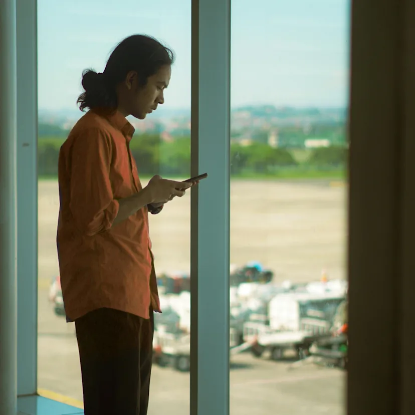 Hombre dentro de un aeropuerto usando su teléfono móvil Hombre dentro de un aeropuerto usando su teléfono móvil