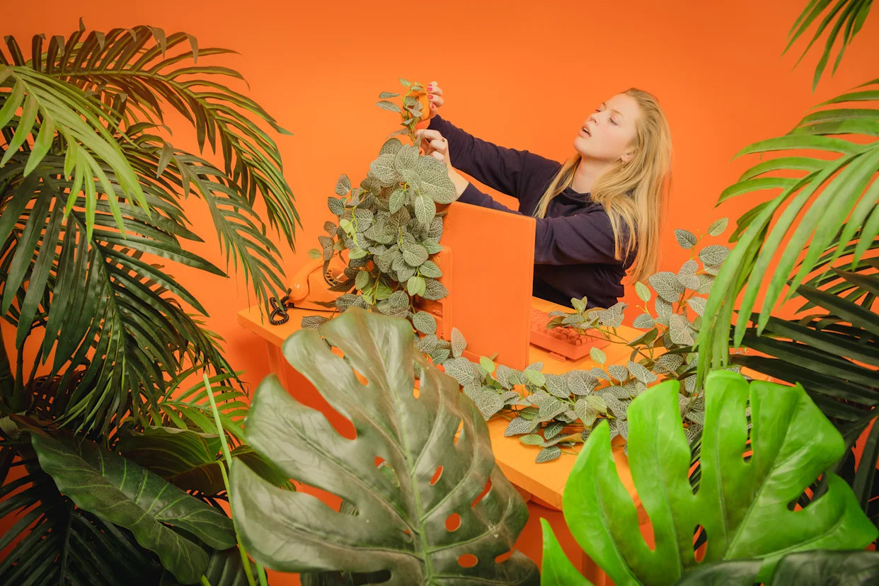 Woman surrounded by plants and holding a stapler.