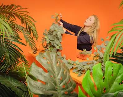 Woman surrounded by plants and holding a stapler.