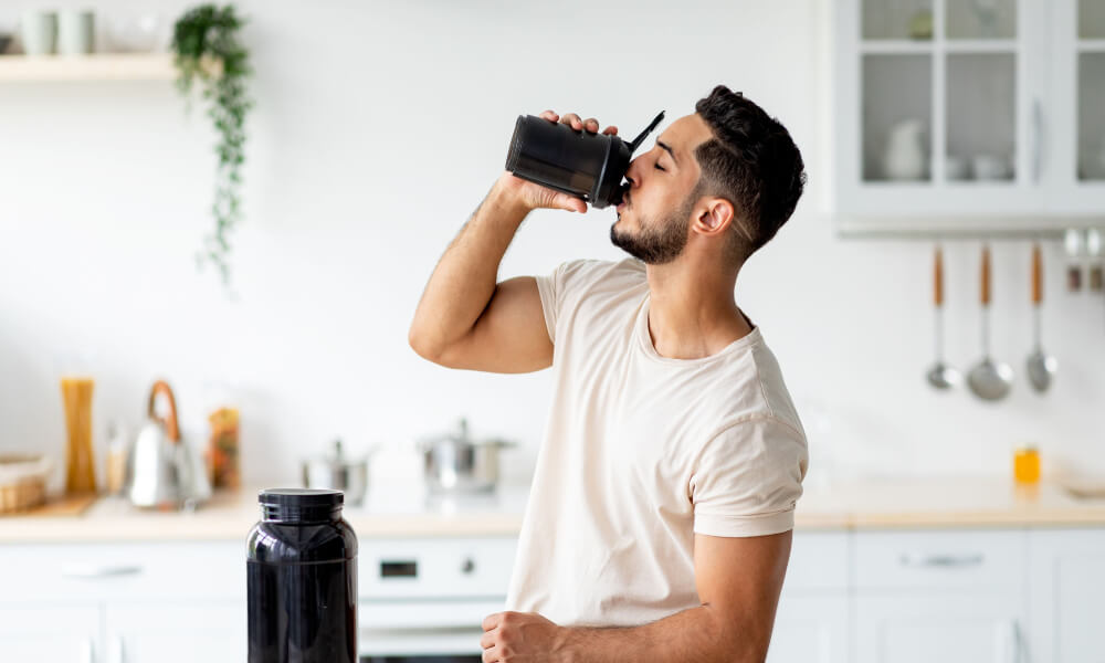 man drinking supplement in shaker bottle