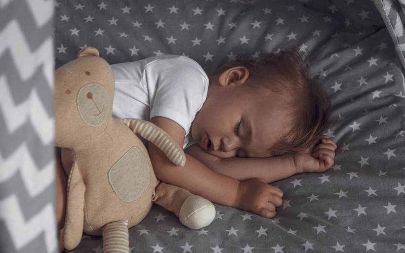 Niño durmiendo al lado de su peluche