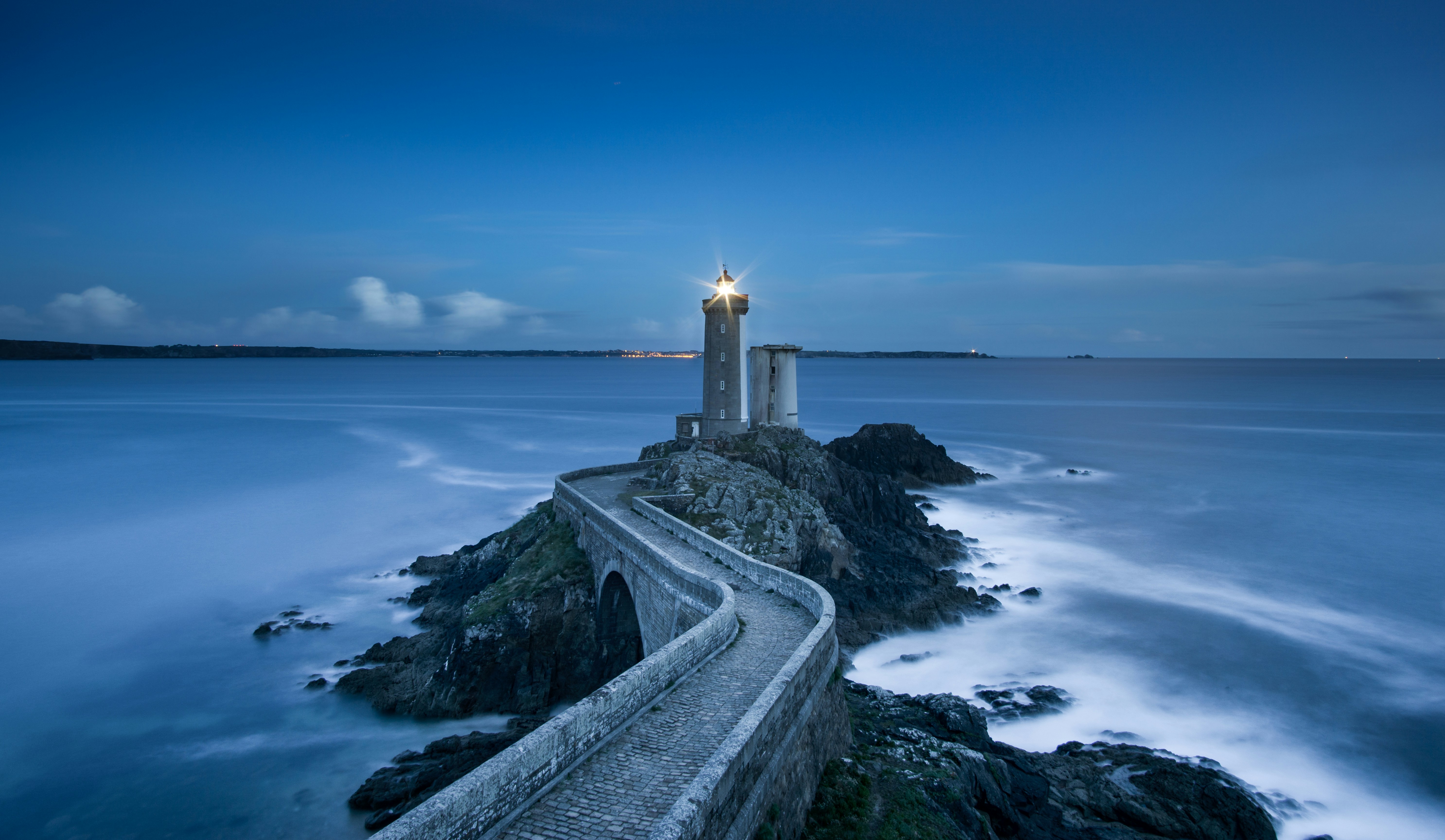 A lighthouse overlooking the water on a foggy day.