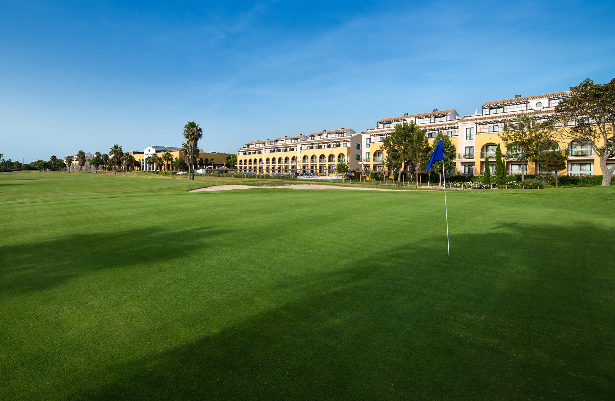 Grønt med flagg foran hotellbygningen ved golfbanen.