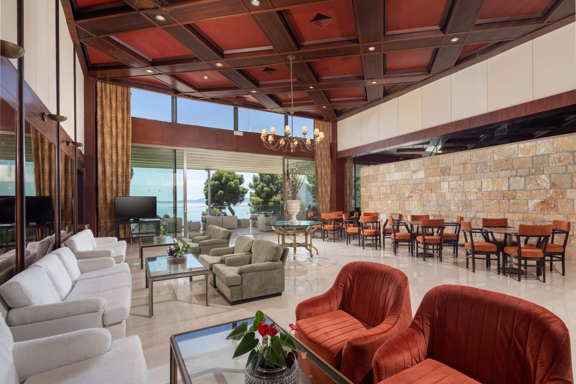 hotellobby med sittgrupper, stora fönster och utsikt mot havet