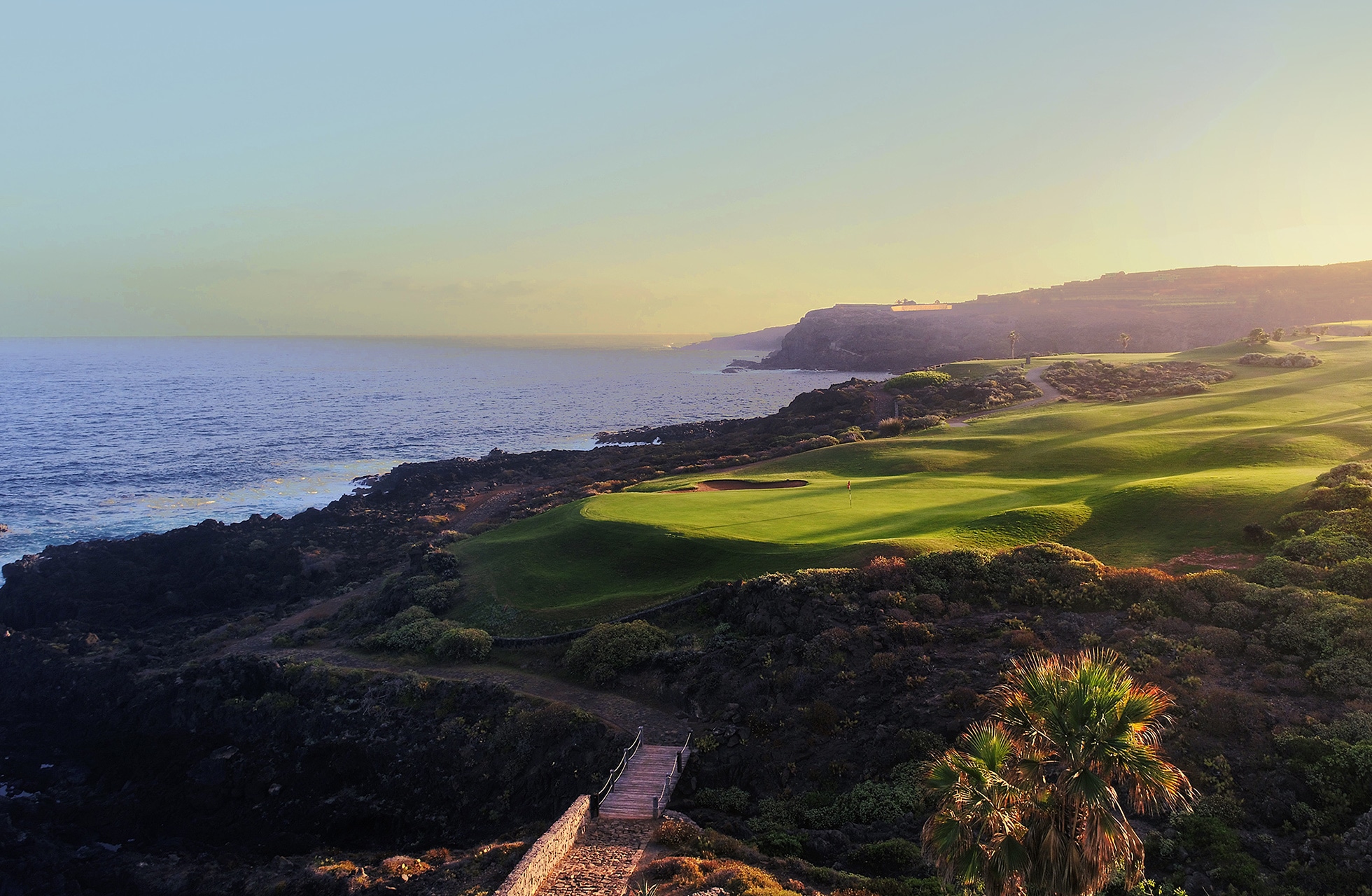 fairwayer på buenavista golf langs kysten med atlanterhavet til venstre, klippelandskap og grønne spilleflater i varmt kveldslys