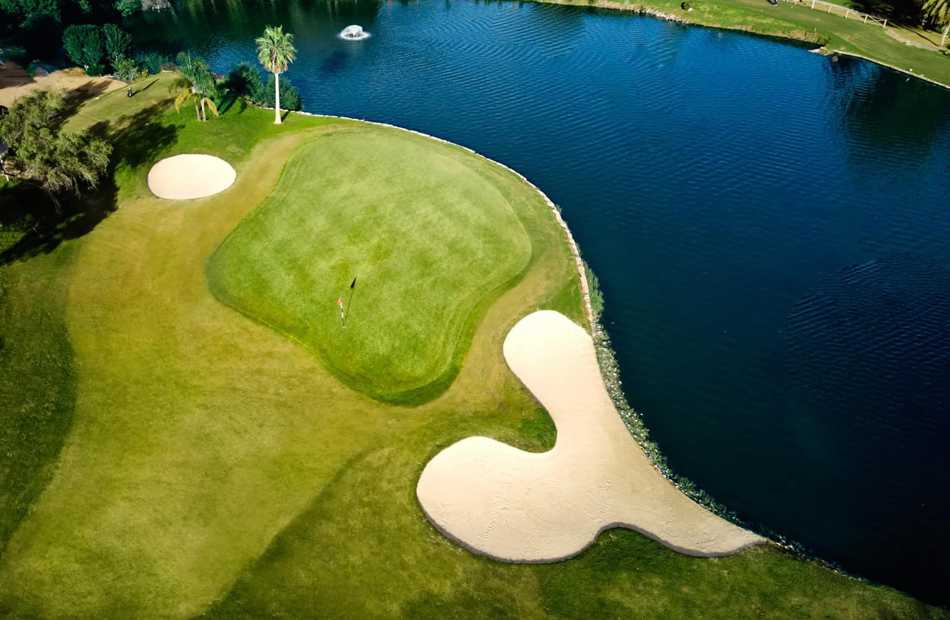 flyfoto av golfgreen på el paraiso golf, omgitt av vannhinder med to bunkere og gressområder i parklandskap