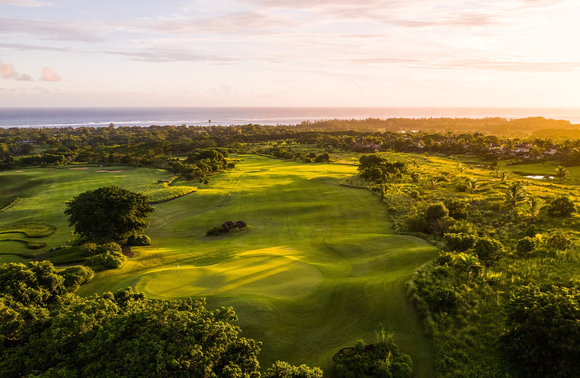luftbilde av heritage golf club le château med grønne fairwayer og greener i bølgende landskap, omgitt av trær i varmt kveldslys