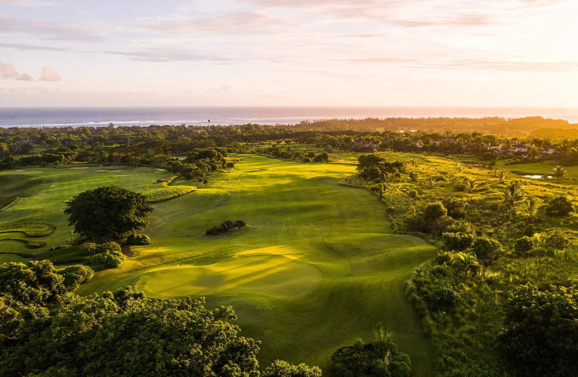 luftbilde av heritage golf club le château med grønne fairwayer og greener i bølgende landskap, omgitt av trær i varmt kveldslys