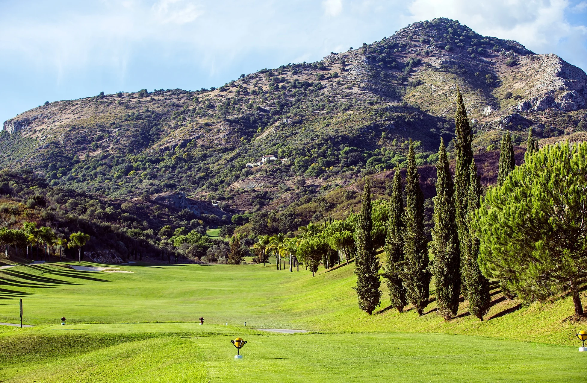 bred fairway på villa padierna golf i åpen dal, kantet av sypresser og trær med fjell i bakgrunnen i mykt dagslys