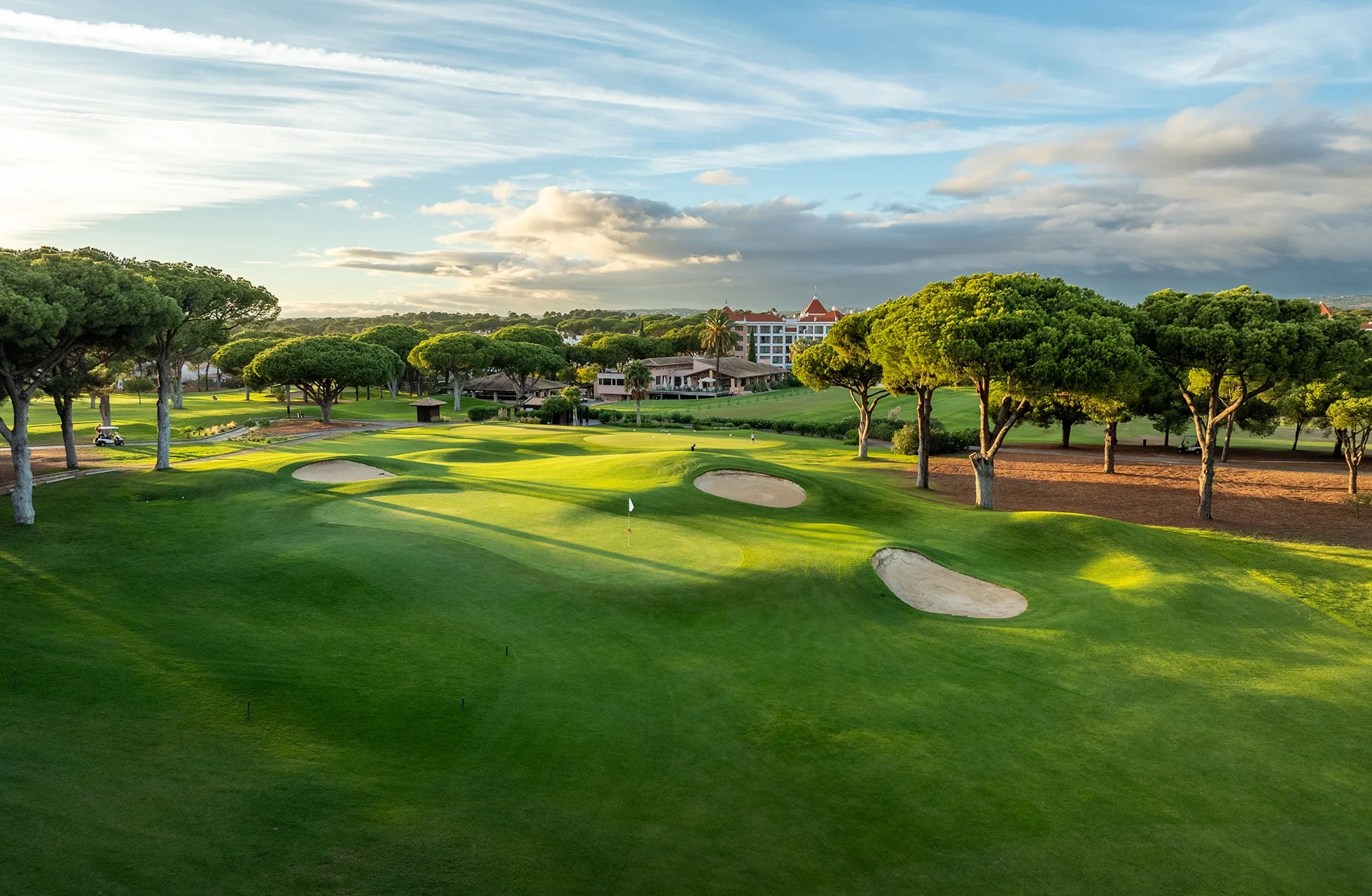panoramautsikt over en grønn golfbane i vilamoura med fairwayer, bunkere og furutrær i solrikt landskap