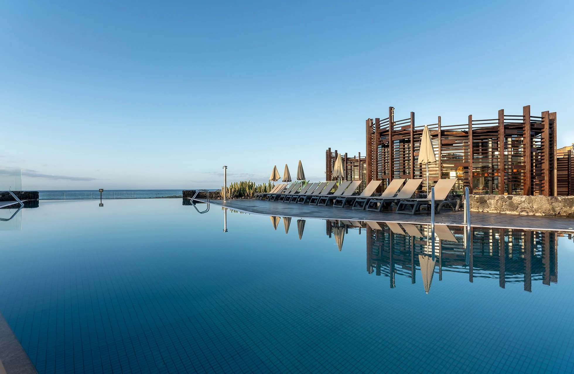 infinity-allas barceló tenerifellä, aurinkotuolit veden äärellä ja näkymä atlantin valtamerelle.