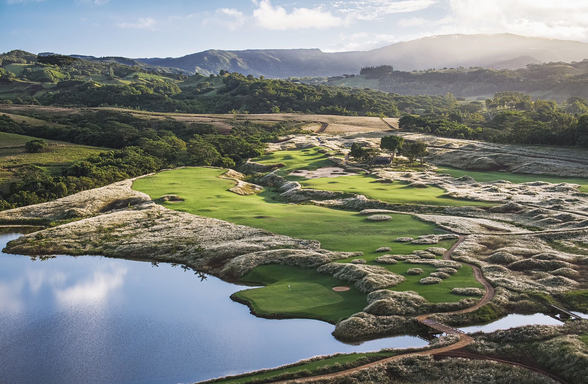 linksbane på heritage golf club la réserve golf links med grønne spilleflater blant klippeformasjoner, vannparti og kupert landskap