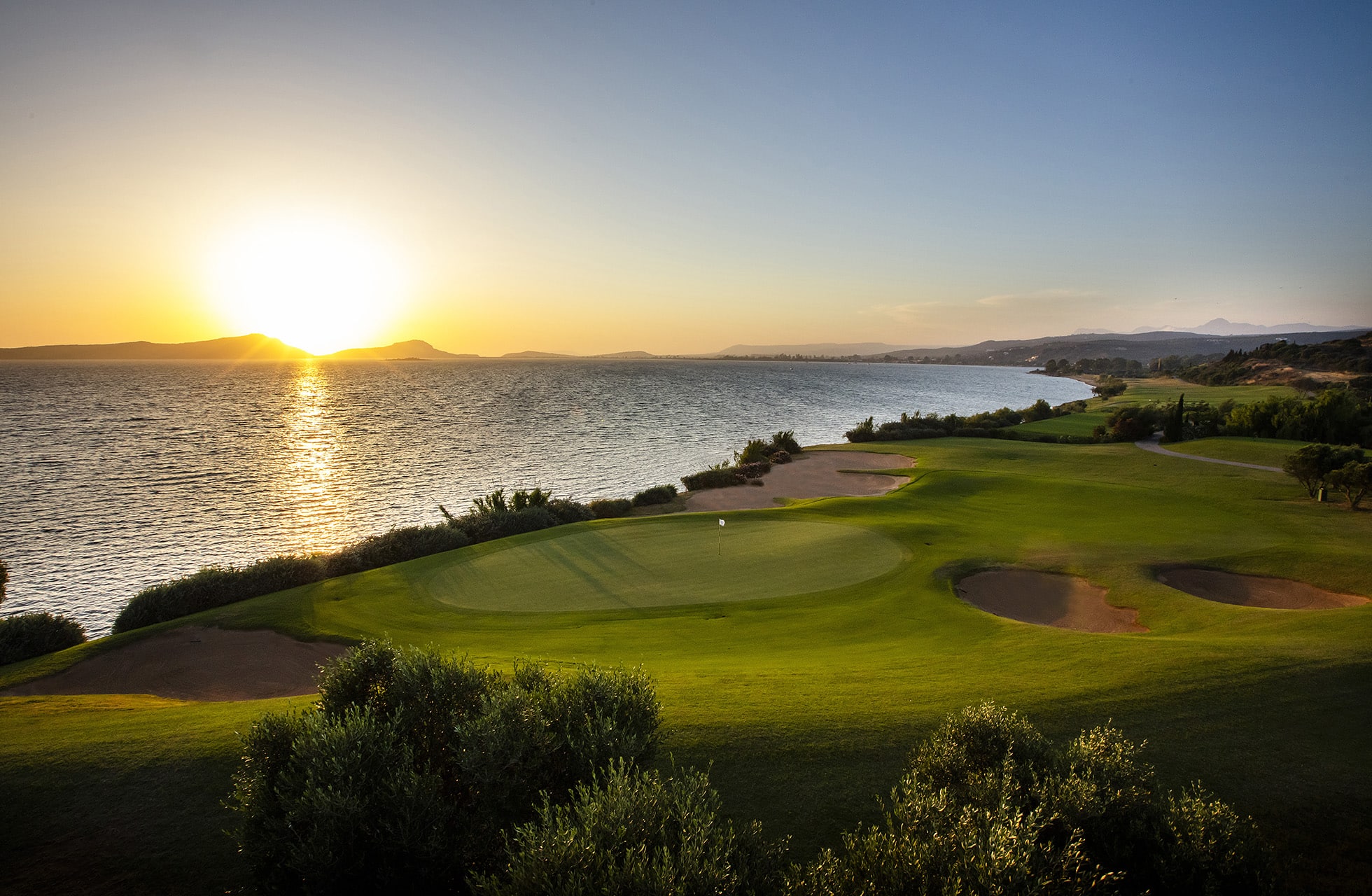 utsikt over green og bunkere på the bay course, costa navarino, med solen lavt over havet