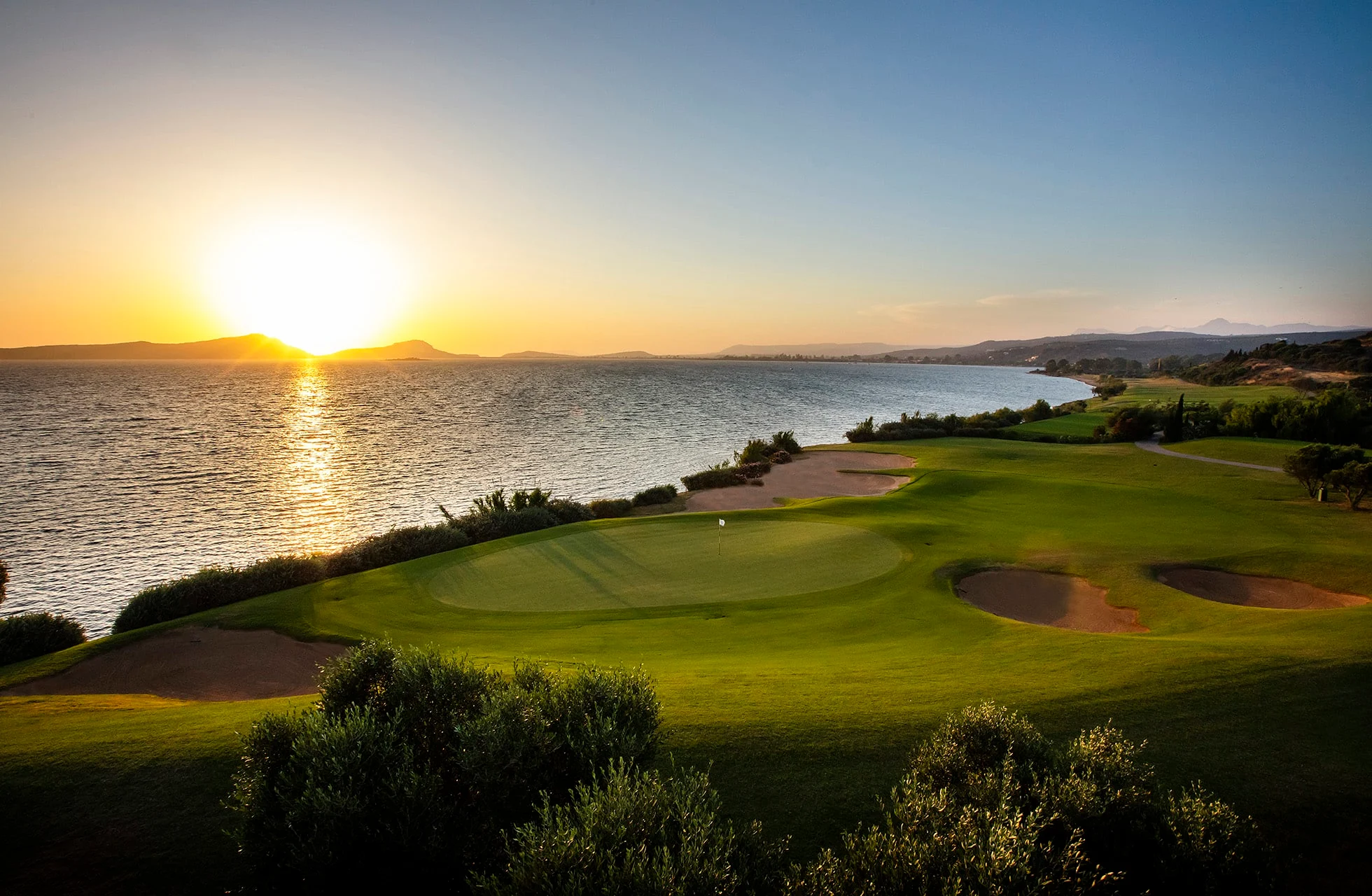 utsikt over green og bunkere på the bay course, costa navarino, med solen lavt over havet