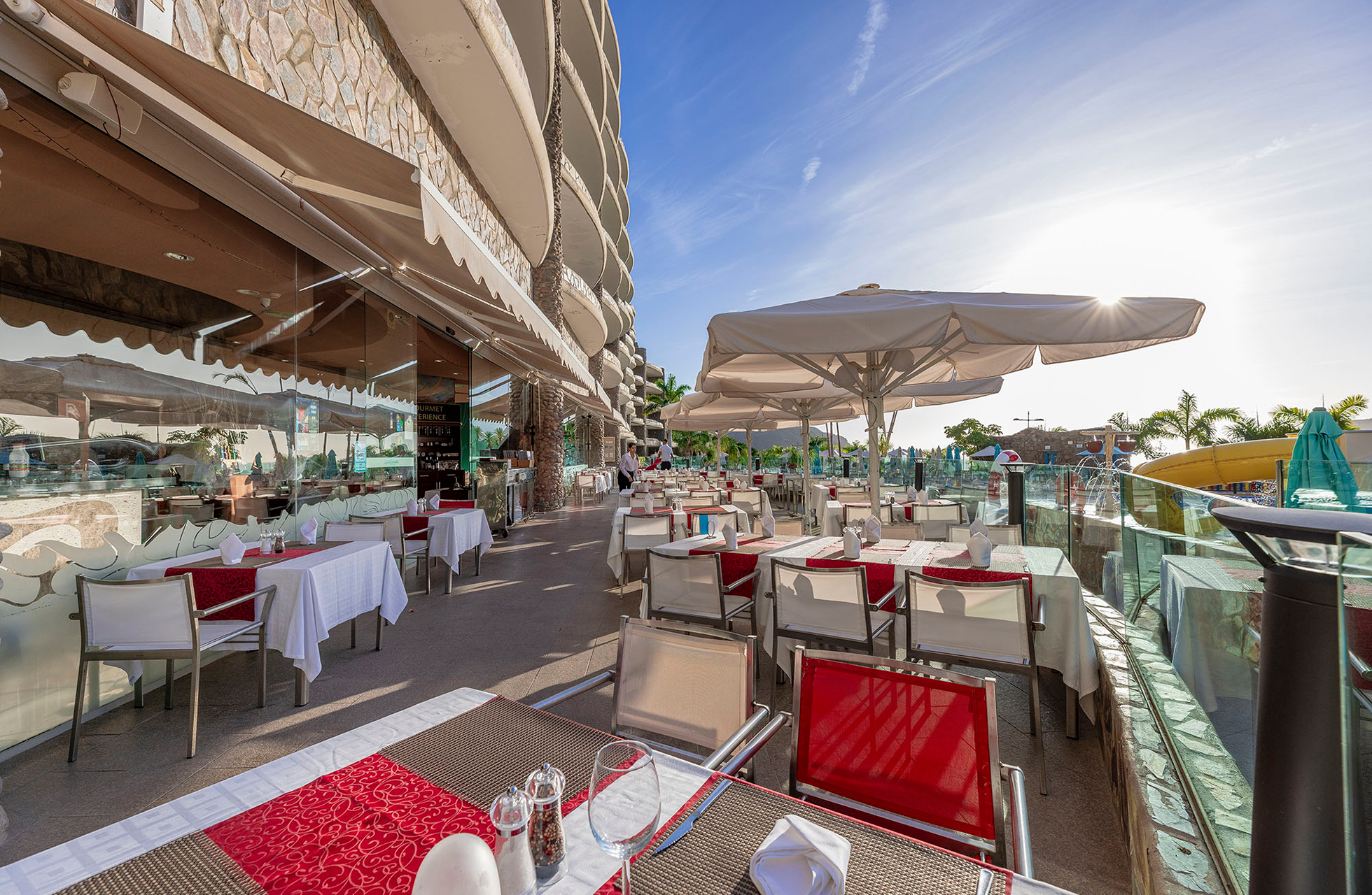 utendørs restaurant på anfi emirald club med dekkede bord, parasoller og glassrekkverk på terrasse i hotellmiljø i dagslys