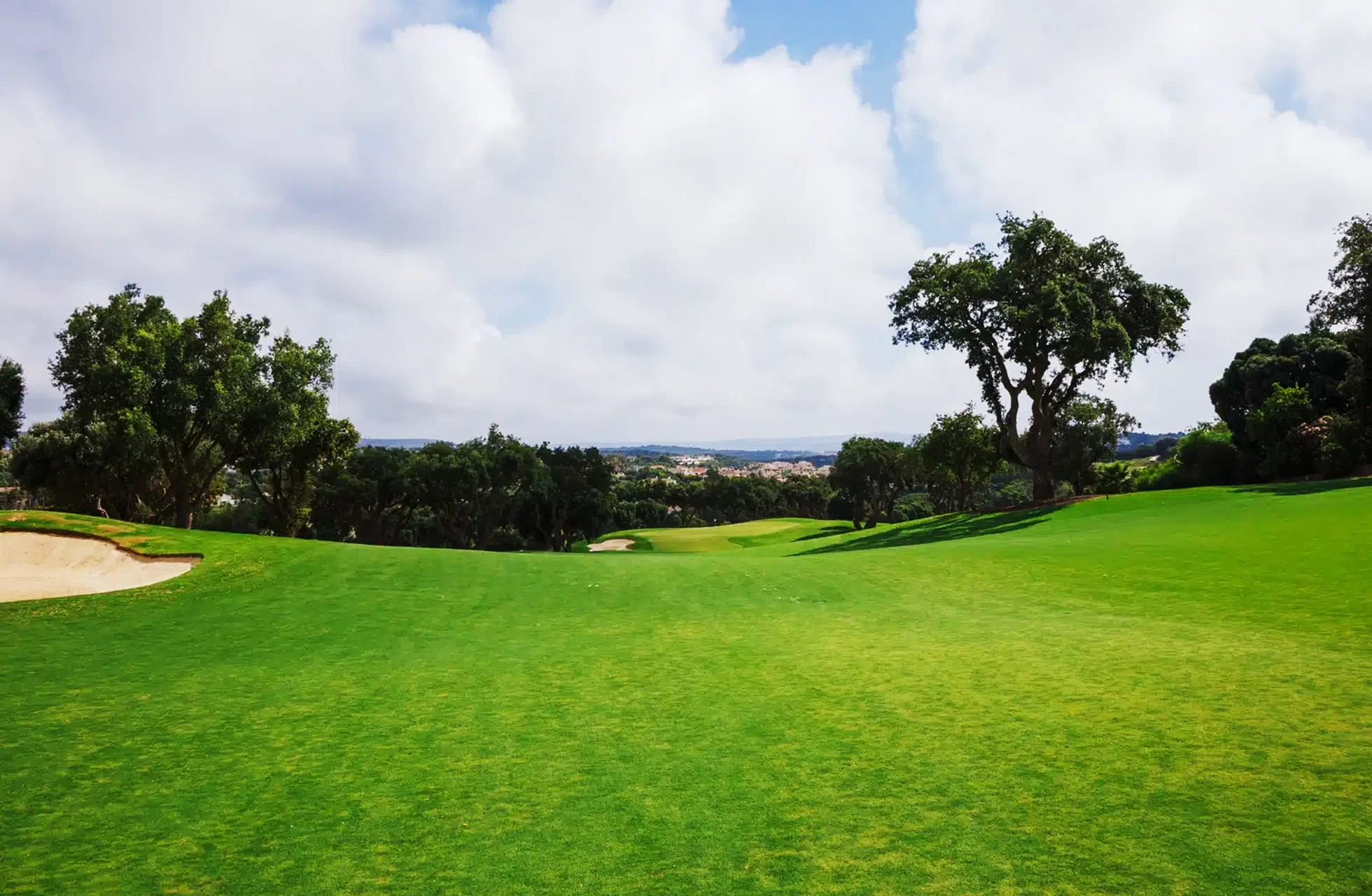 bred fairway i parklandskap på san roque new course, med bunker, trær og åpent landskap i lyst dagslys