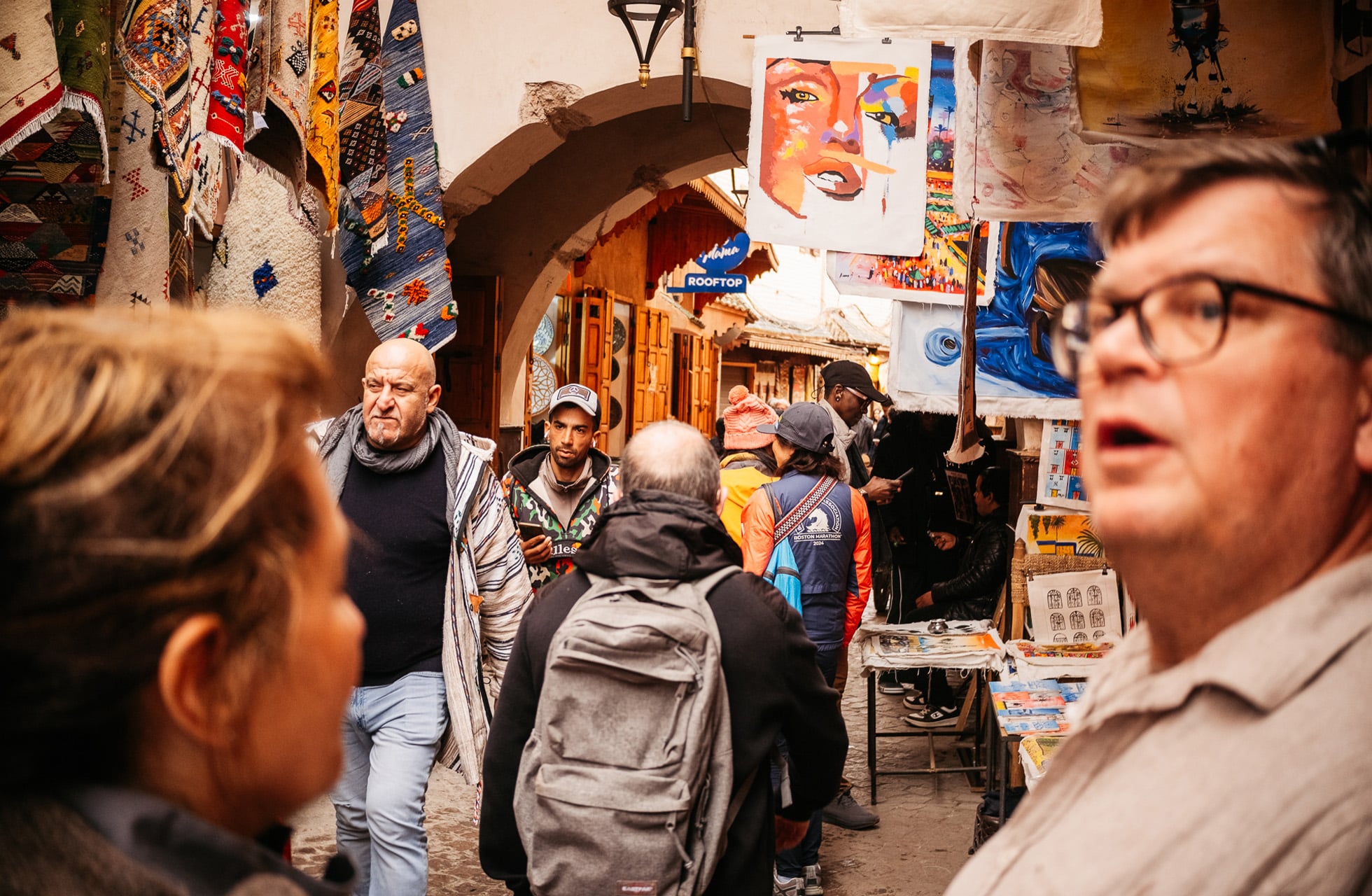 smal markedsgate med mange mennesker som beveger seg mellom butikker og boder med kunst og varer