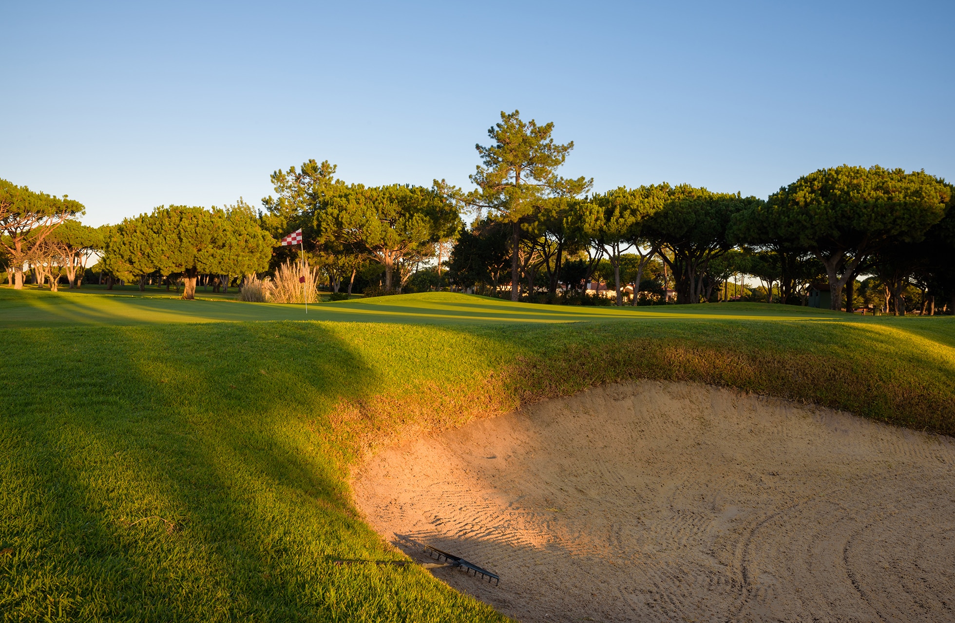 sandbunker ved green med trær og villaer i bakgrunnen på vila sol golfbane.
