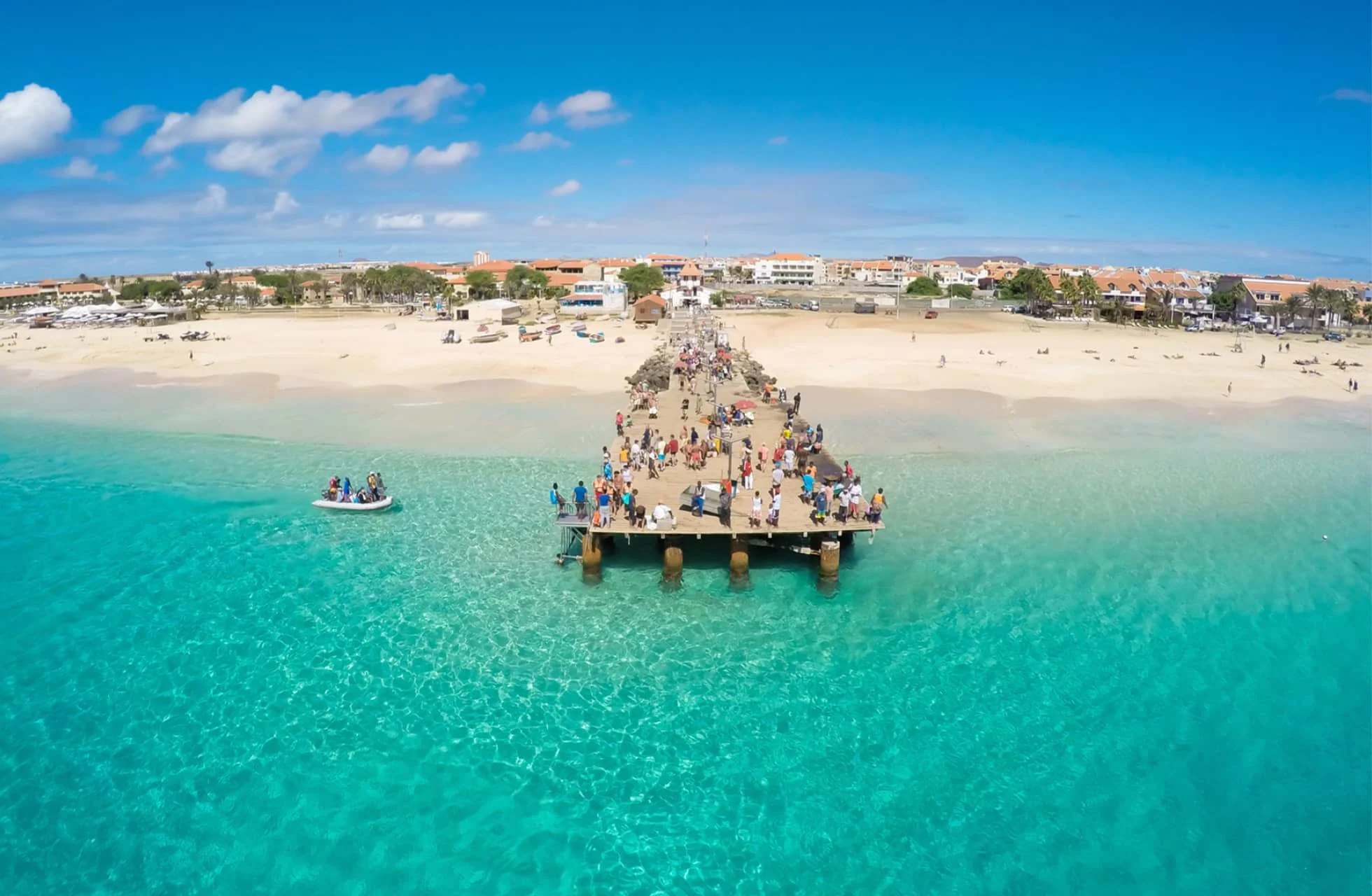kap verde, strand med turkosblått vatten och en stor brygga med mycket folk på.