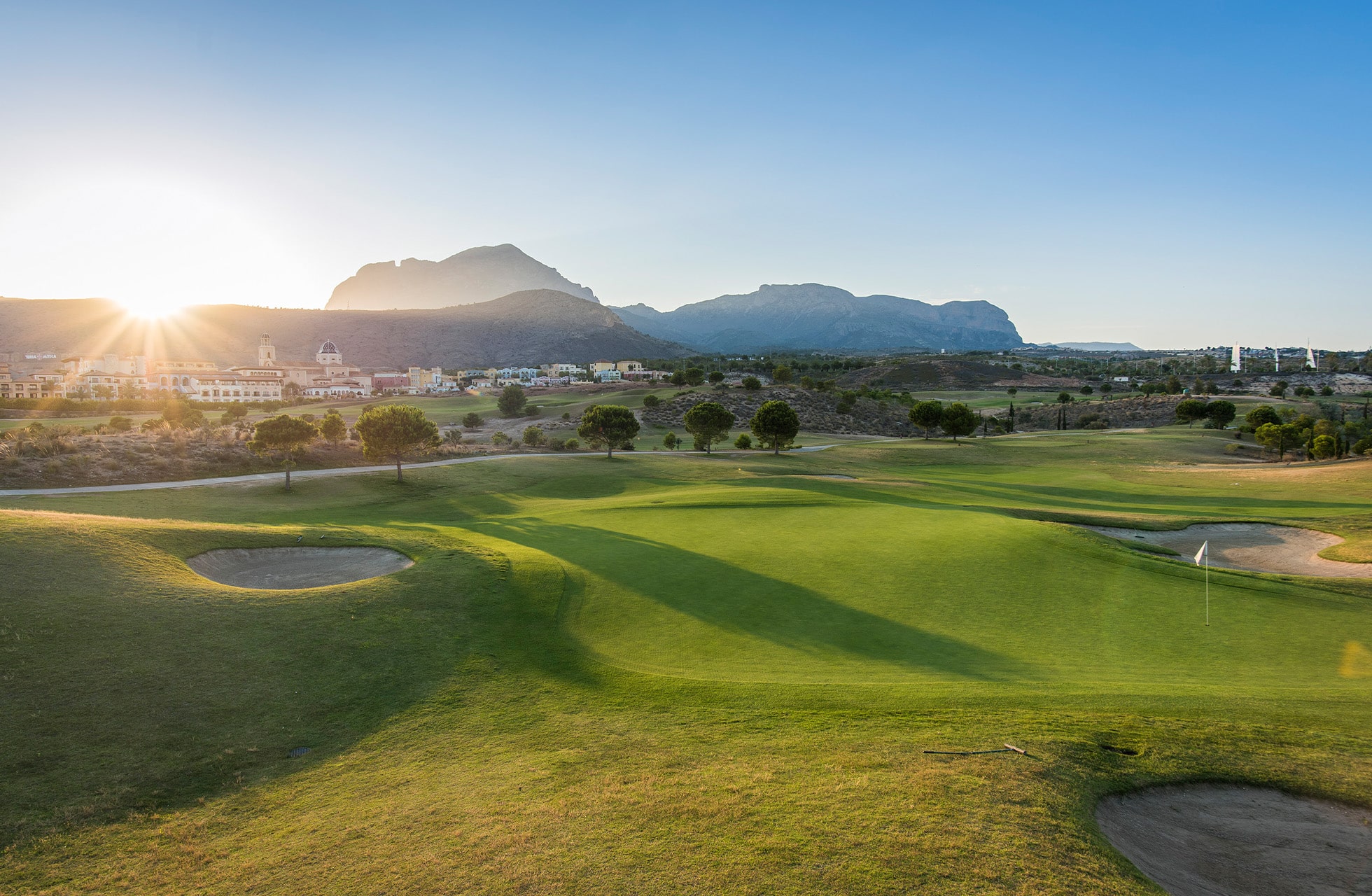 golfbane med myke fairwayer og fjell i bakgrunnen