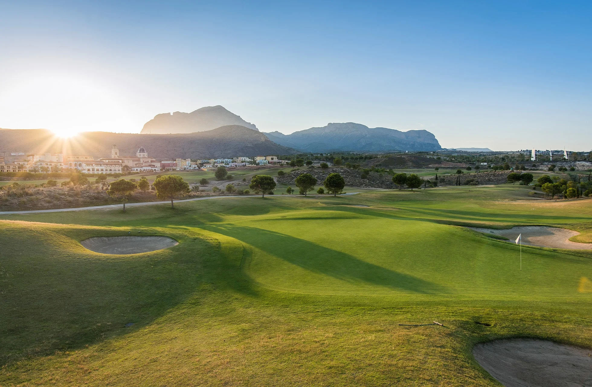 golfbane med myke fairwayer og fjell i bakgrunnen