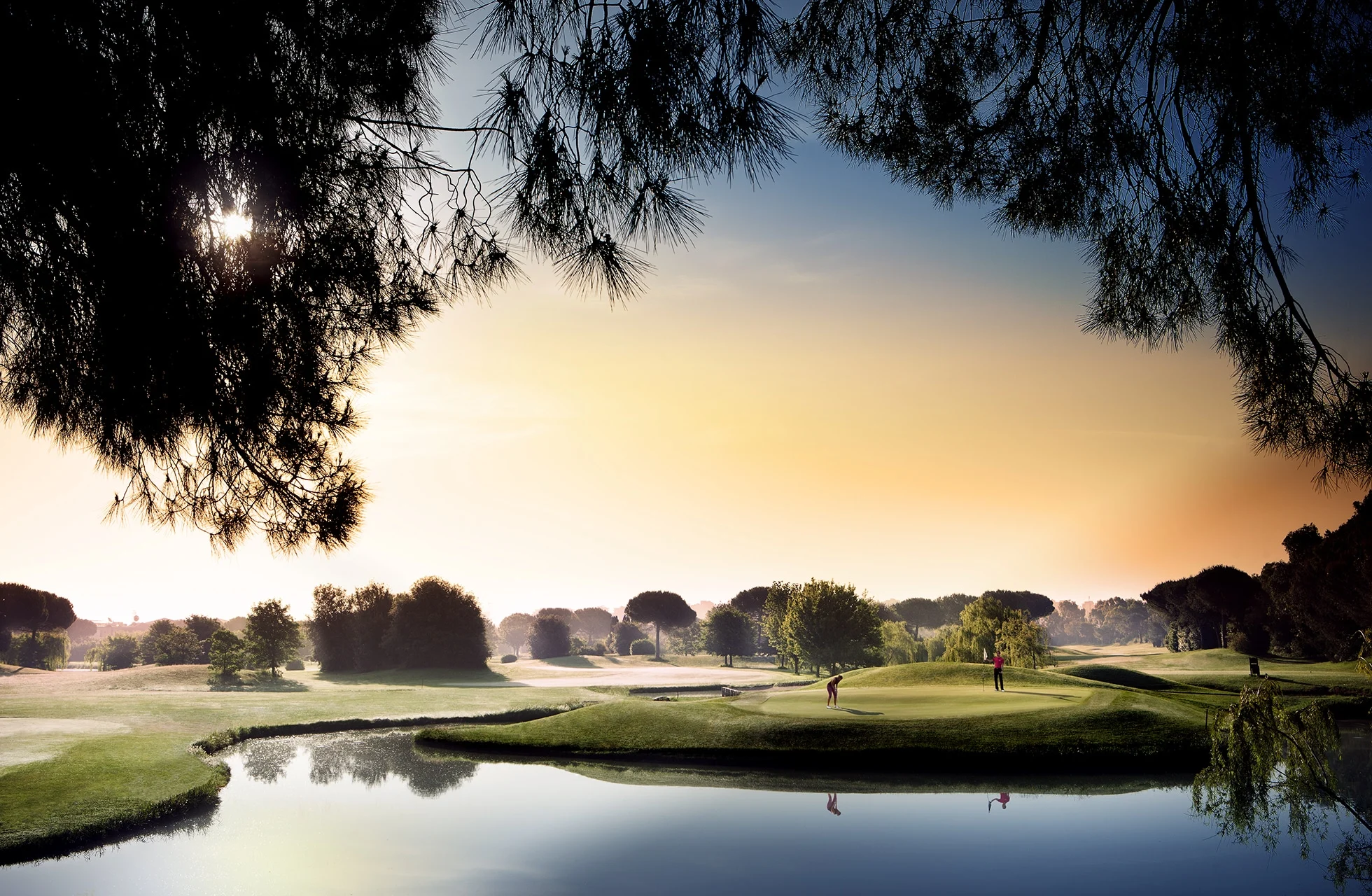 golfspillere på green ved vannhinder på parco de’ medici golf club i varmt kveldslys
