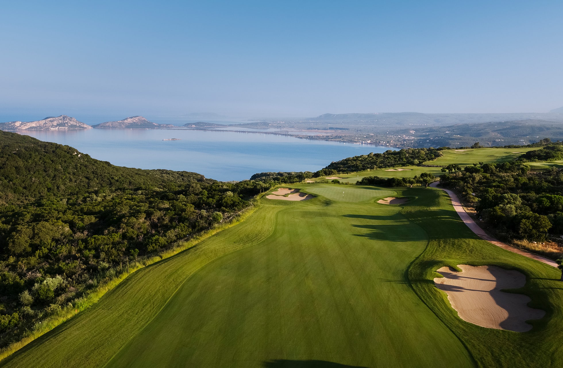 bred fairway på costa navarino olympic course som slynger seg gjennom grønt landskap mot havet