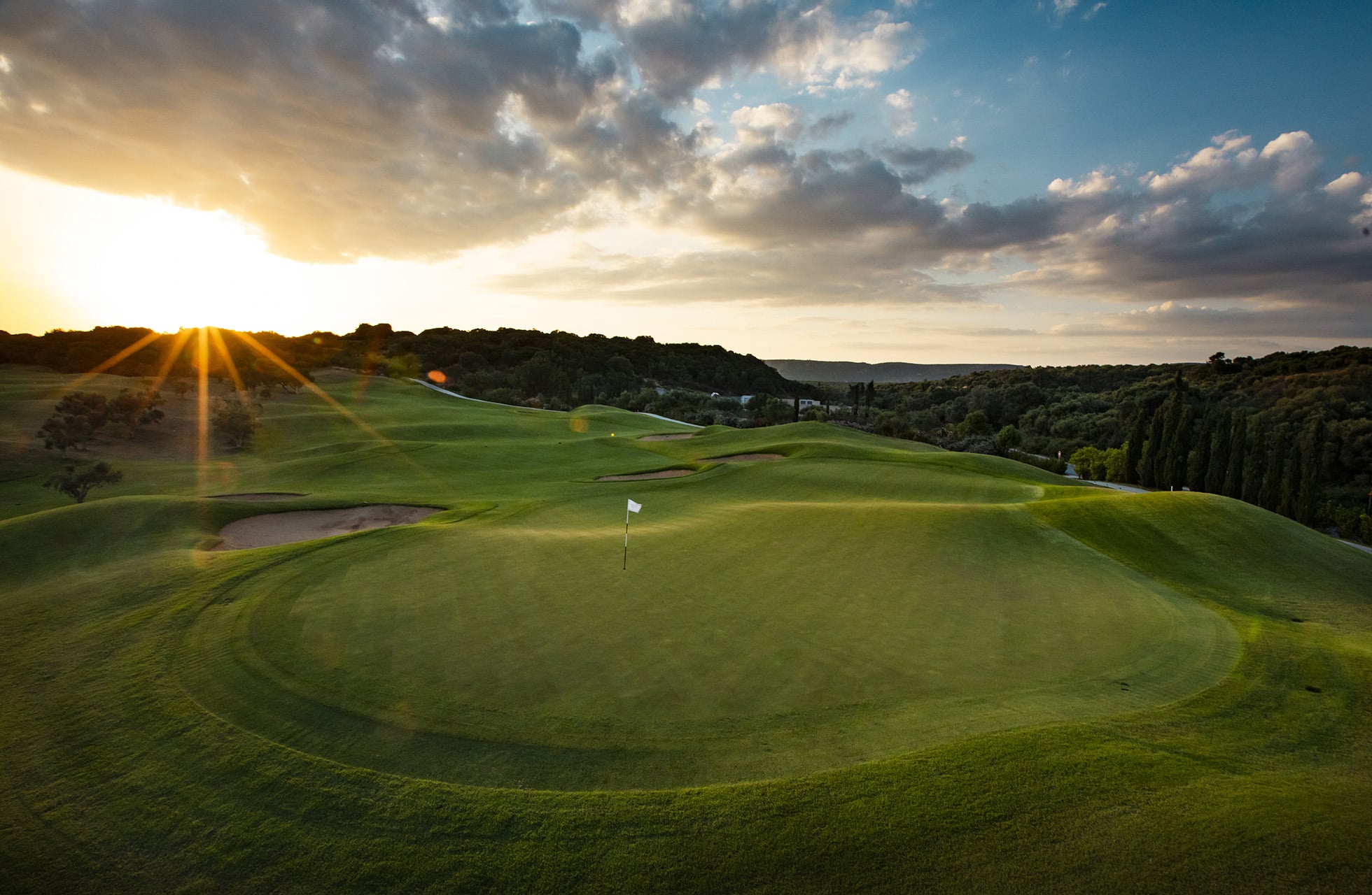 green med flagg på the dunes course costa navarino i solnedgang med bølgende fairwayer