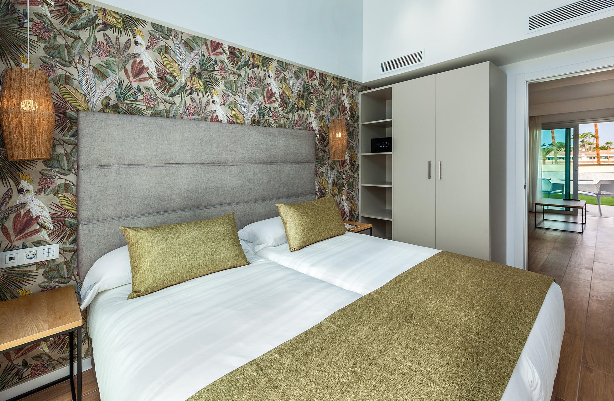 lyst og moderne hotellrom i suite på kumara serenoa med dobbeltseng, botanisk tapet, dekorative lamper og utgang til terrasse i dagslys