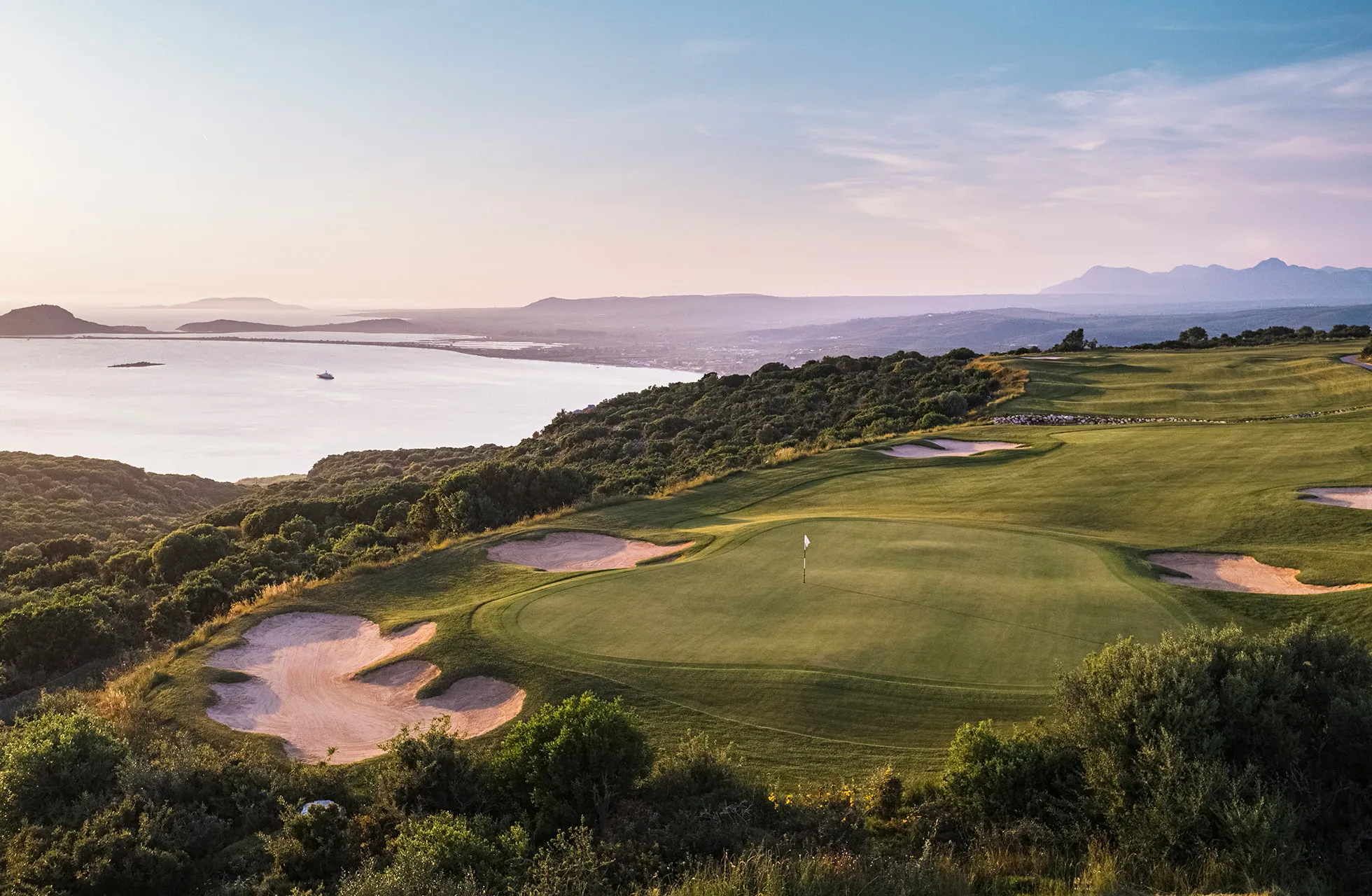 hevet green på costa navarino olympic course med bunkere og kystlinje i kveldslys