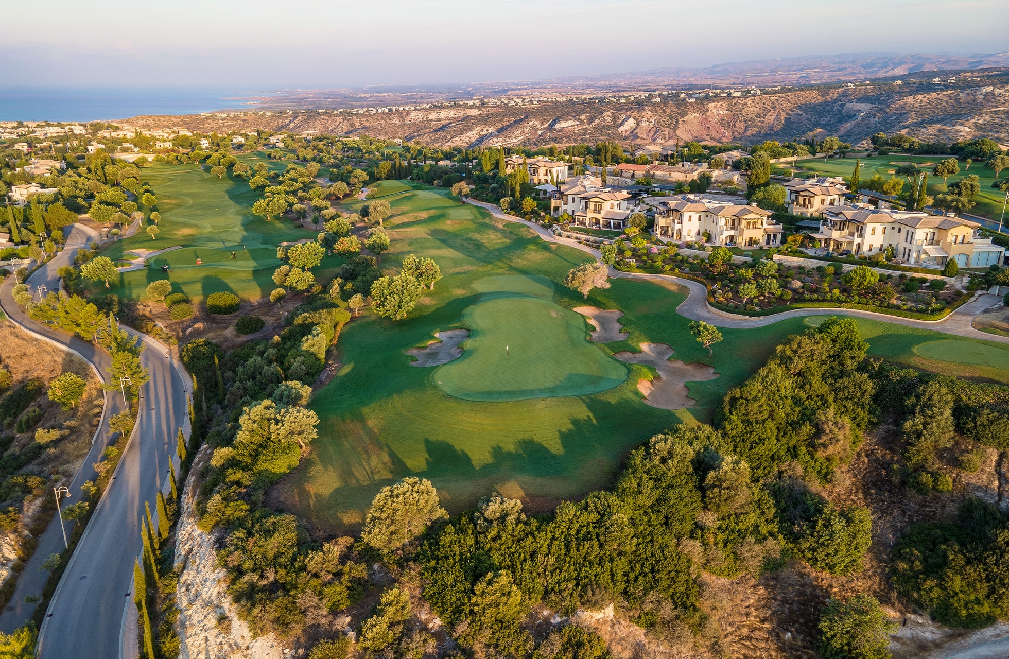 flyfoto av aphrodite hills golf med fairways omgitt av boliger og grøntområder