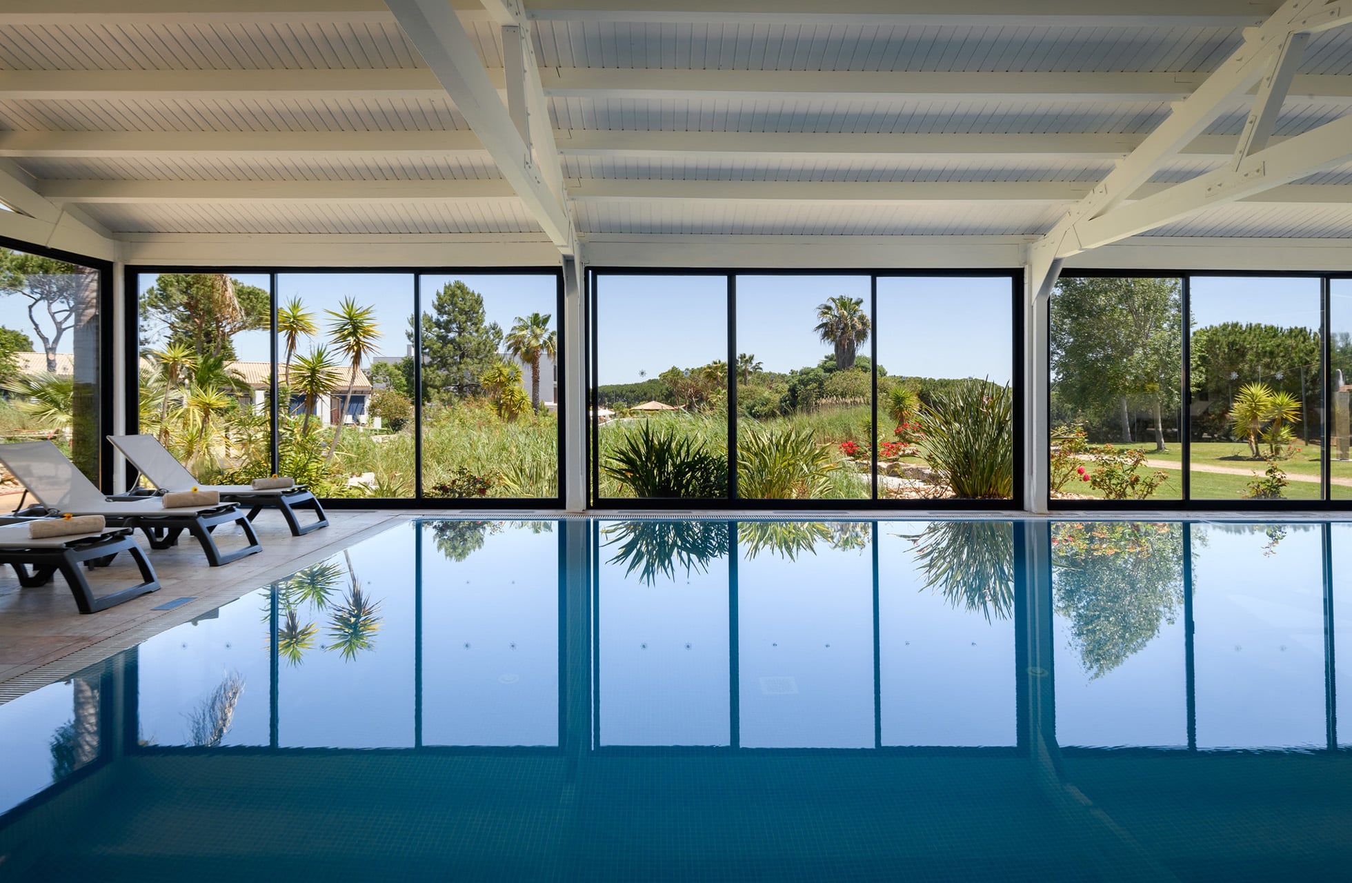 innendørsbasseng ved vila sol resort med stille bassengområde, solsenger og store vinduer med utsikt mot grønn hage og golfbane