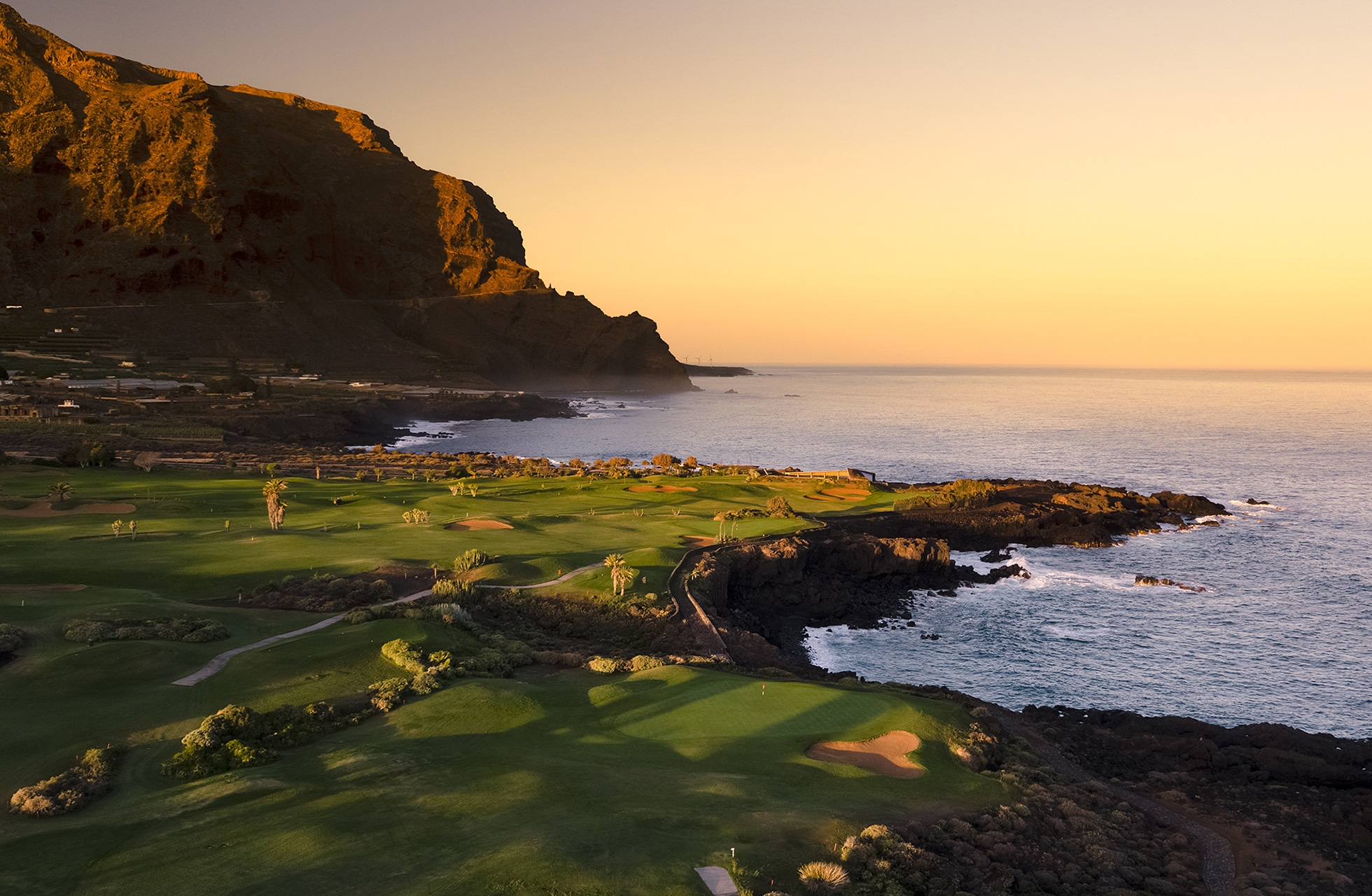 kystnære fairwayer på buenavista golf i gyllent kveldslys, med klipper, atlanterhavet og fjell i bakgrunnen