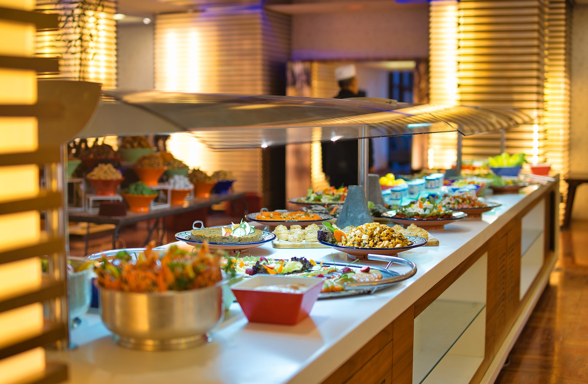 oppdekket buffet med flere retter, salater og varme retter i en moderne hotellrestaurant med varm belysning
