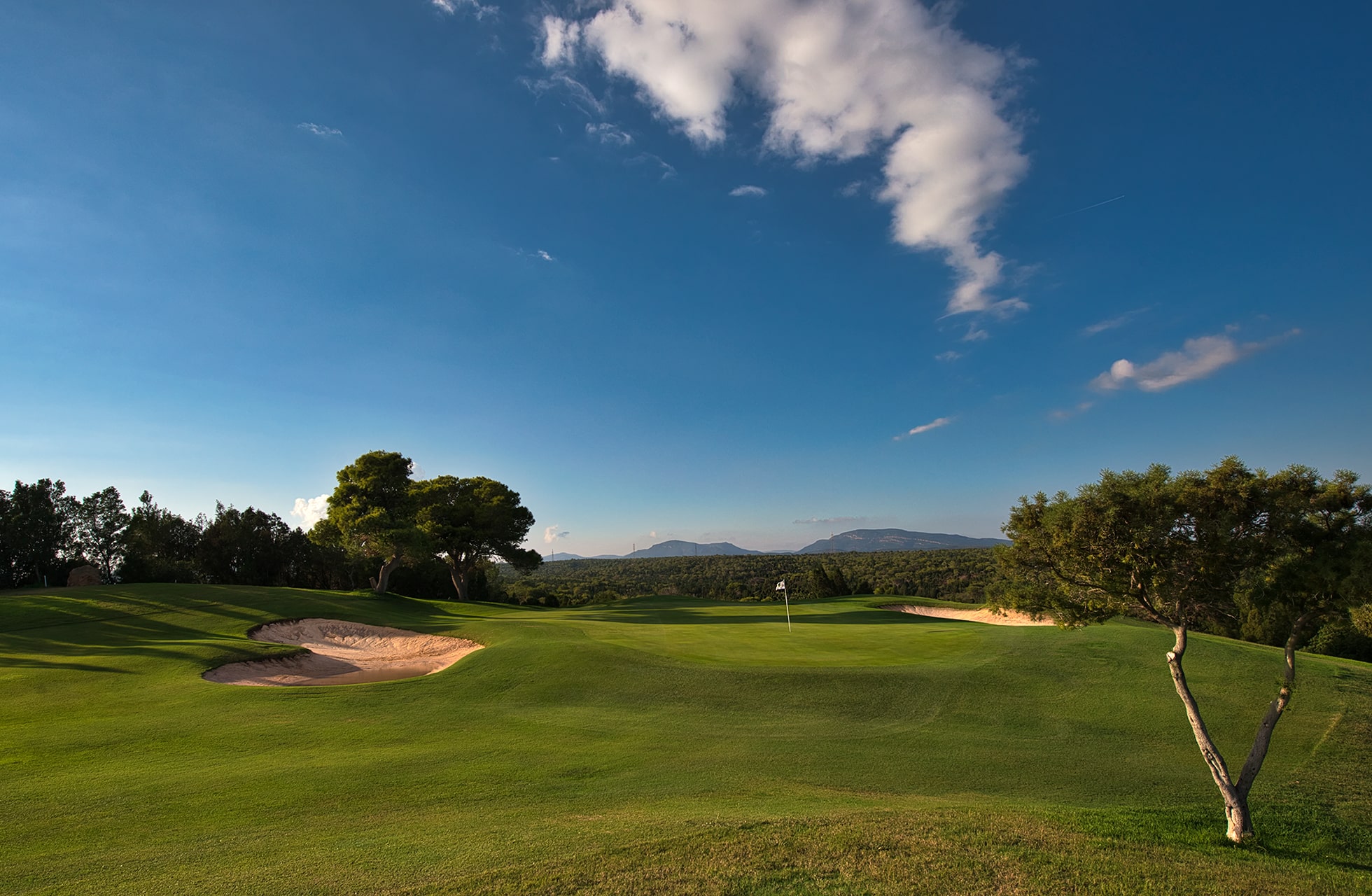 kystnær golfbane i tunisien med green og bunker i forgrunnen, havet i bakgrunnen og åpent landskap under dramatisk himmel.