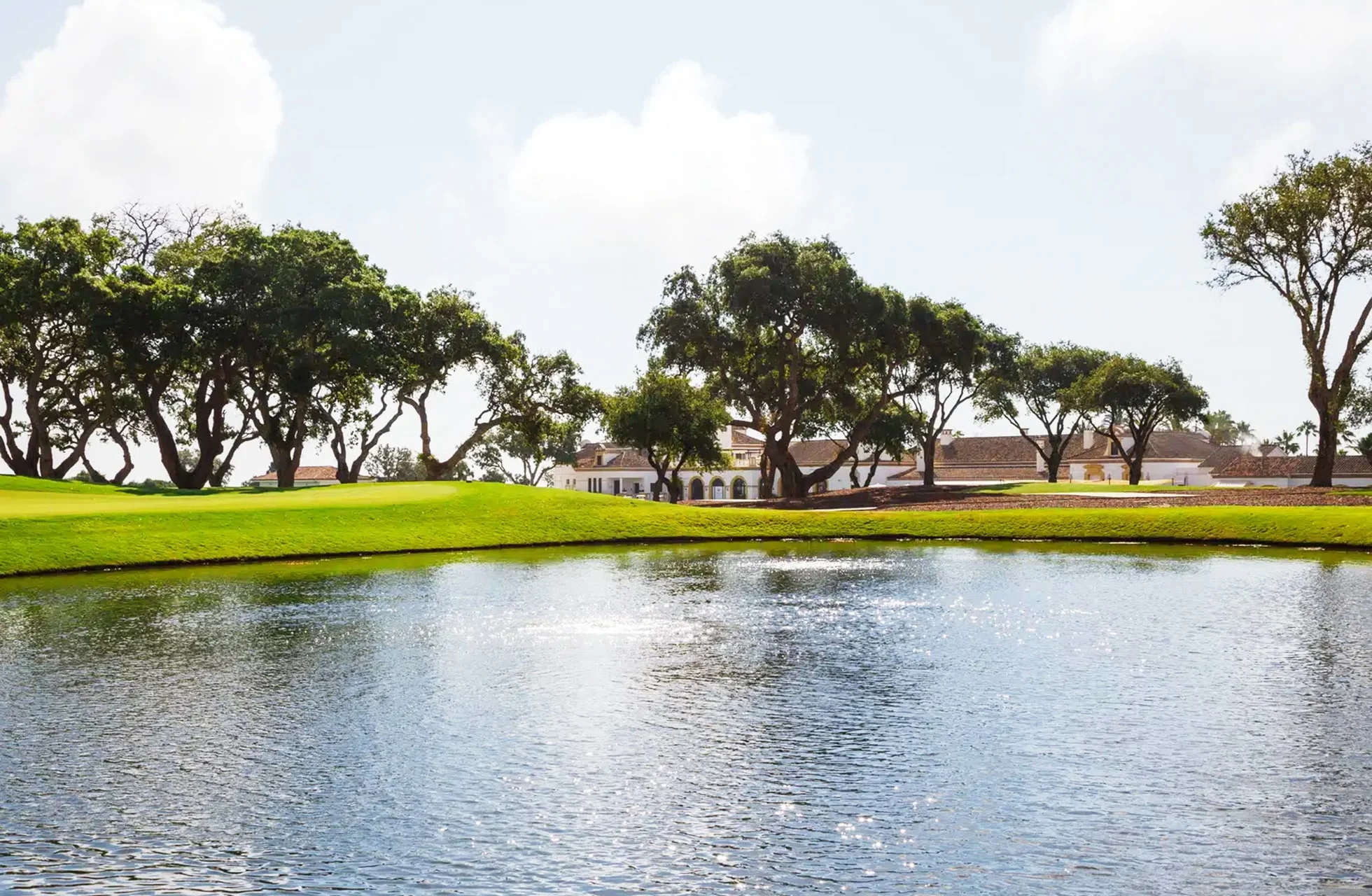vannhinder foran golfgreen og fairway på san roque new course, omgitt av trær og bygninger i lyst dagslys