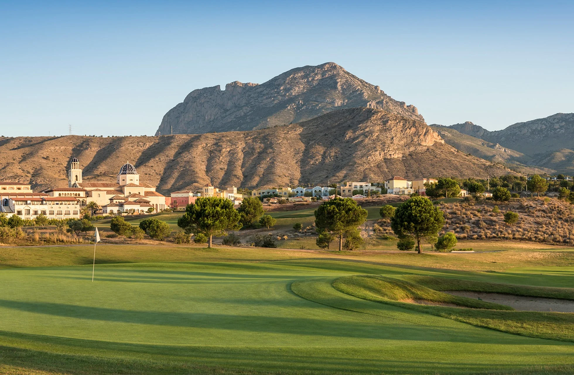 Golfgreen med utsikt over resorten og fjellene.
