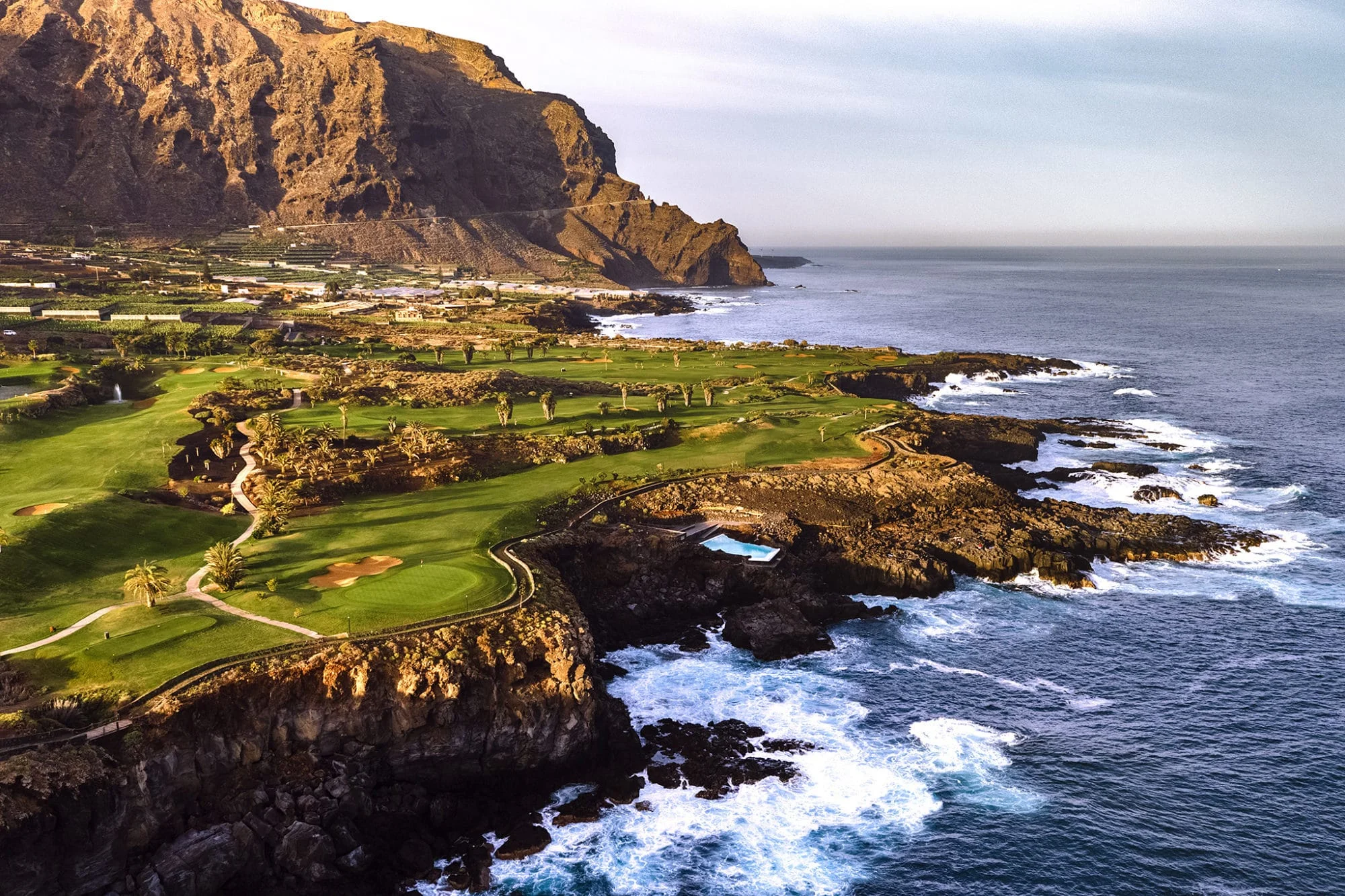 kystnær utsikt over buenavista golf med grønne fairwayer på klipper ved atlanterhavet og fjell i bakgrunnen