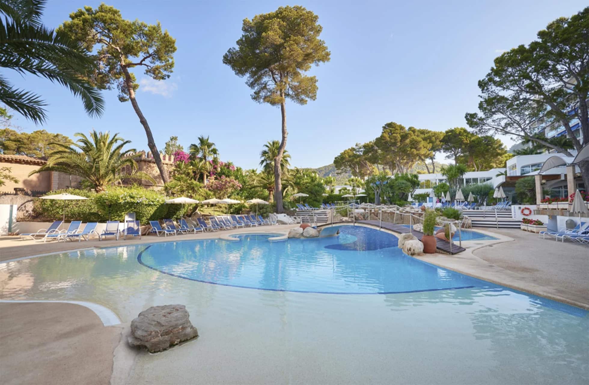utendørs basseng på eurotel punta rotja med myke former, solsenger og parasoller, omgitt av furutrær, palmer og hotellbygninger i dagslys