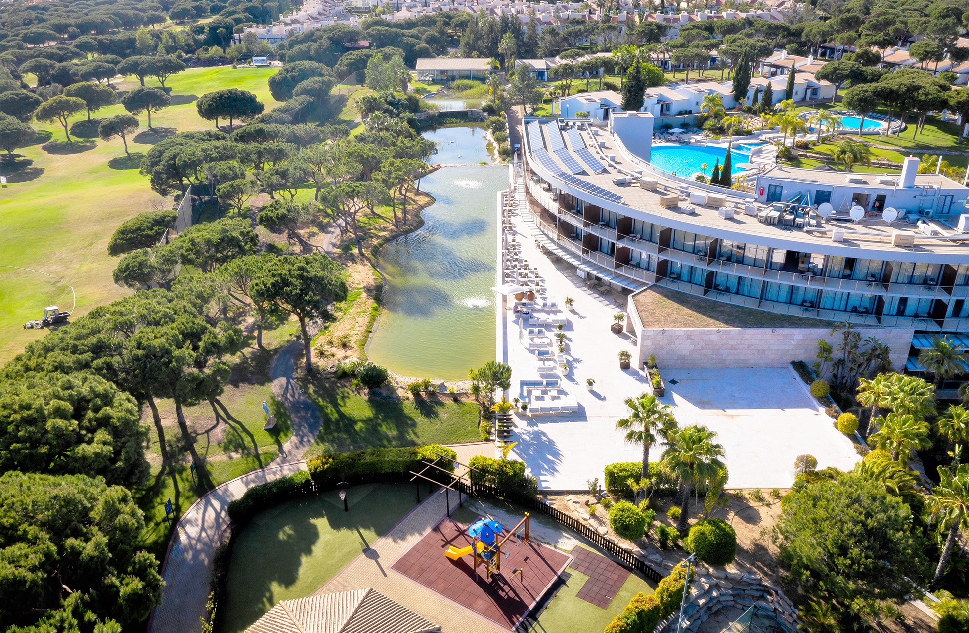 flyfoto av vila sol resort med hotellbygning, bassengområde og omkringliggende golfbane med grønne fairwayer, trær og vannhindre