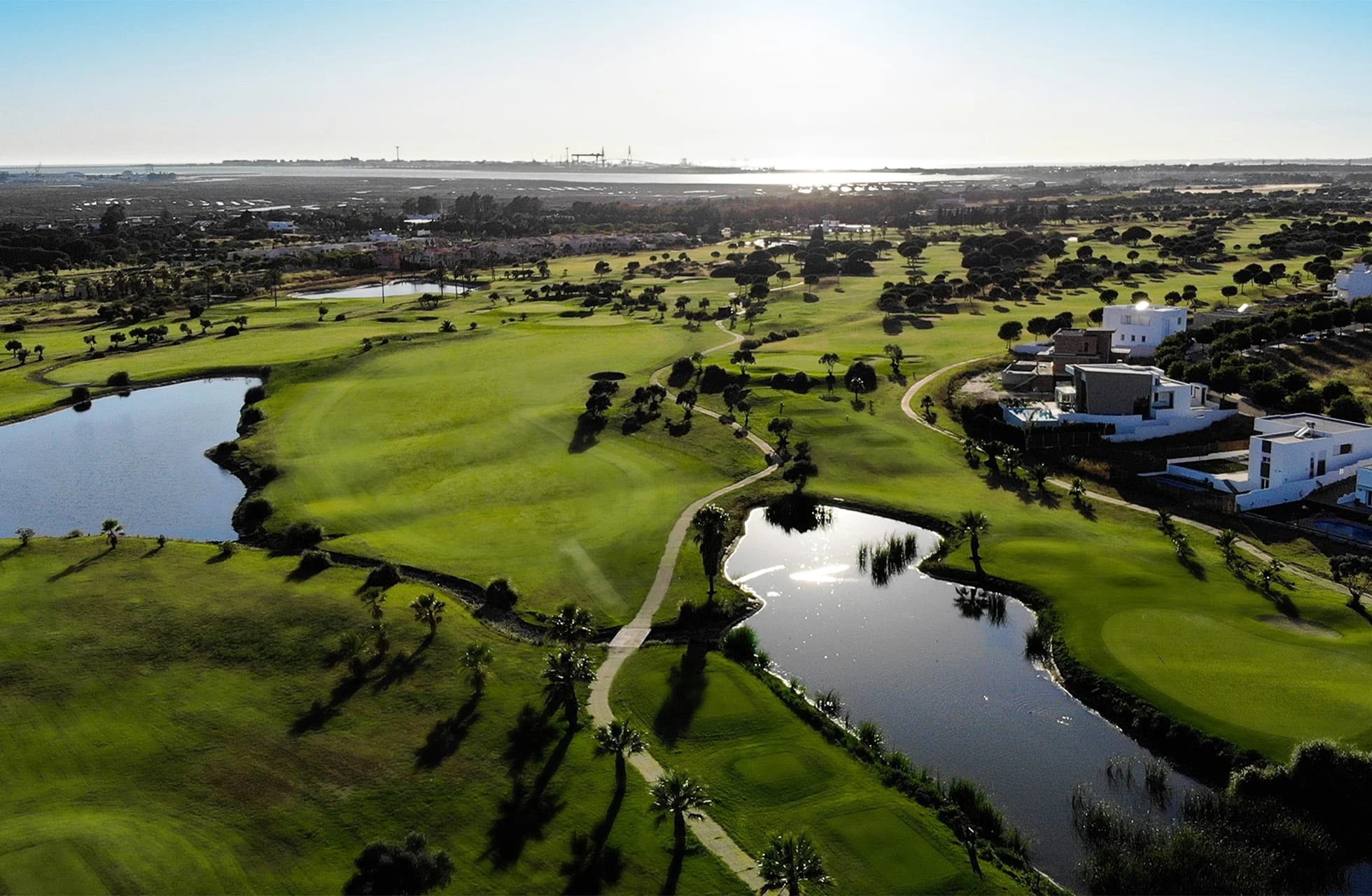 Luftfoto av en golfbane med flere innsjøer, fairwayer og omkringliggende landskap